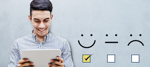 A customer is holding a tablet with a checked box on excellent smiley, while there are two boxes such as moderate and poor smilies being unchecked.