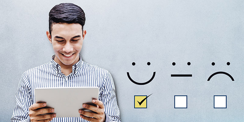 A customer is holding a tablet with a checked box on excellent smiley, while there are two boxes such as moderate and poor smilies being unchecked.
